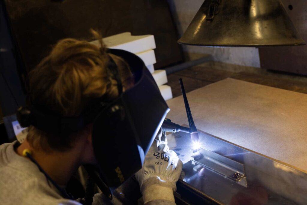 Smed der svejser metaldele med beskyttelsesmaske