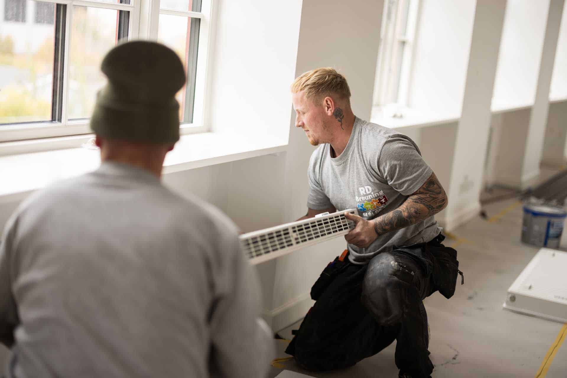 To montører installerer varmeenhed i privat bolig